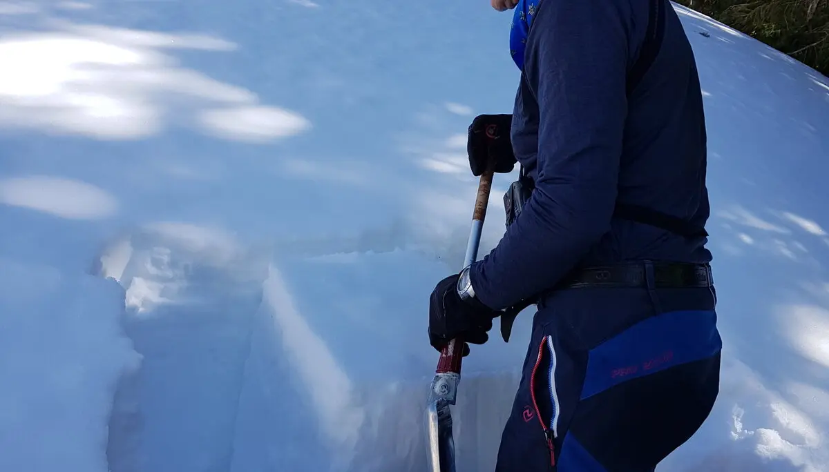 Ein Mann untersucht mit einer Schaufel die Schneeschichten zur Lawinenbeurteilung. | © DAV Dortmund