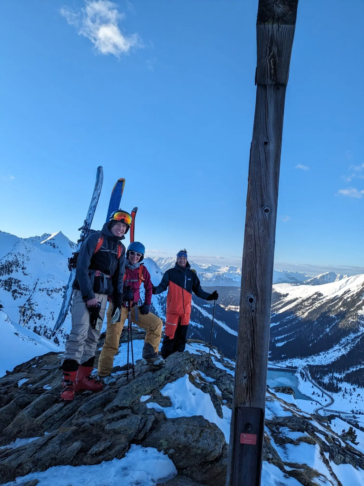 Drei Skitourengeher*innen stehen auf einem verschneiten Gipfel mit Holzkreuz. | © DAV Dortmund