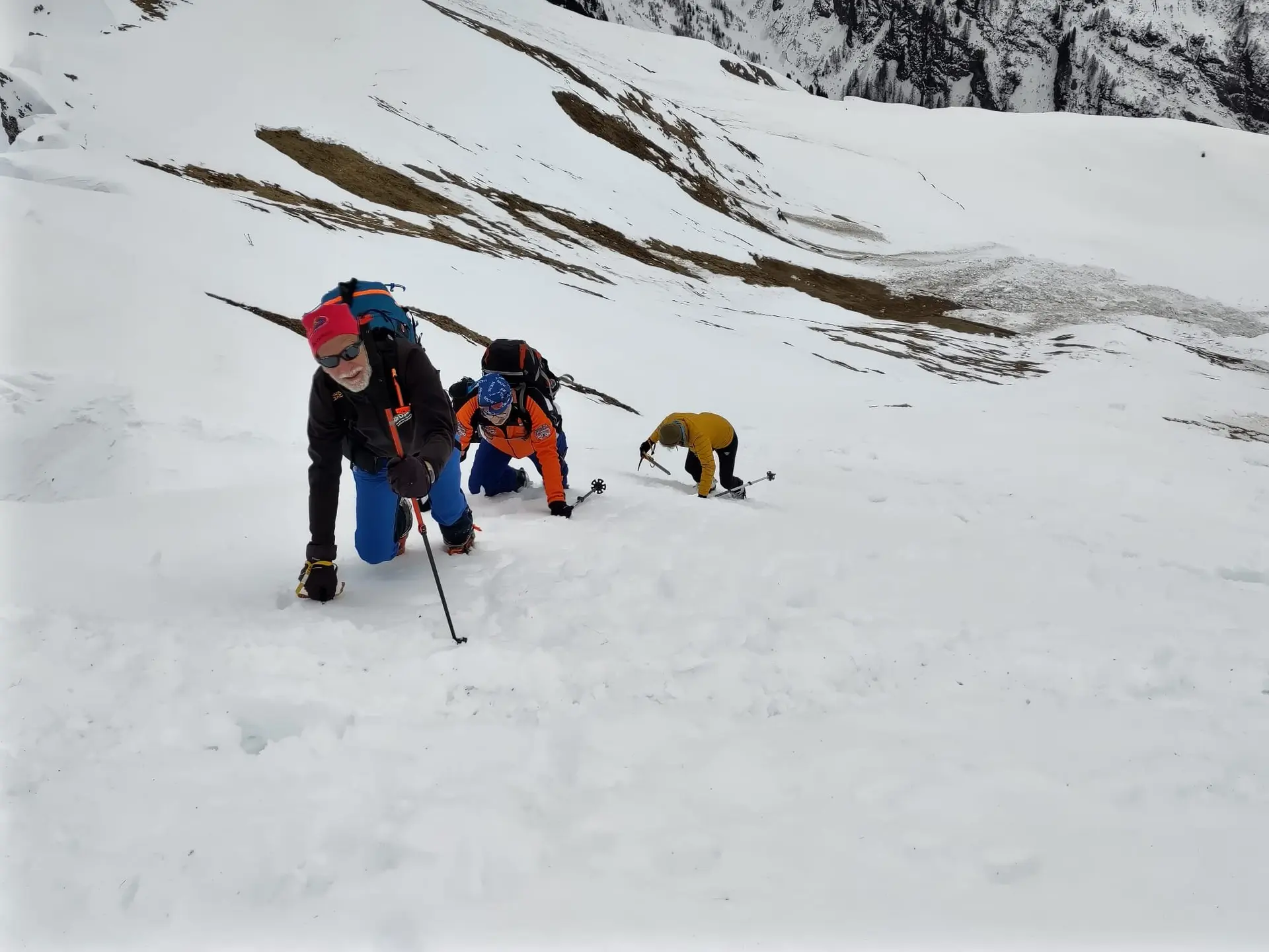 Drei Skitourengeher*innen klettern einen steilen Schneehang auf allen Vieren hinauf, mit Skiern auf dem Rücken. | © DAV Dortmund