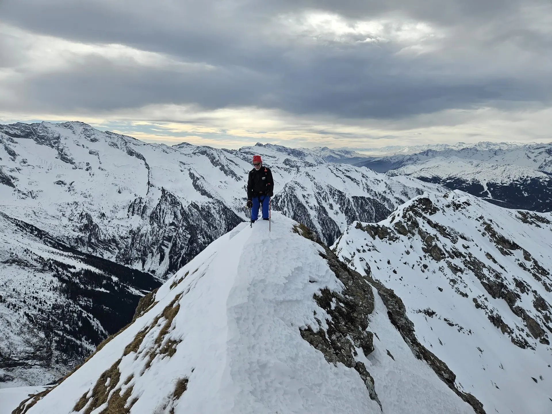Person steht allein auf einem schmalen, verschneiten Grat mit Weitblick über ein Bergpanorama. | © DAV Dortmund