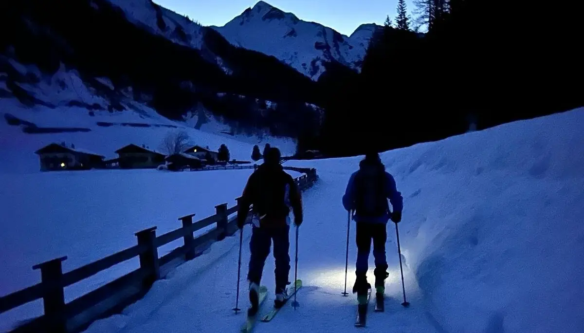 Zwei Personen mit Stirnlampen auf Skiern in verschneiter Landschaft bei Dämmerung. | © DAV Dortmund