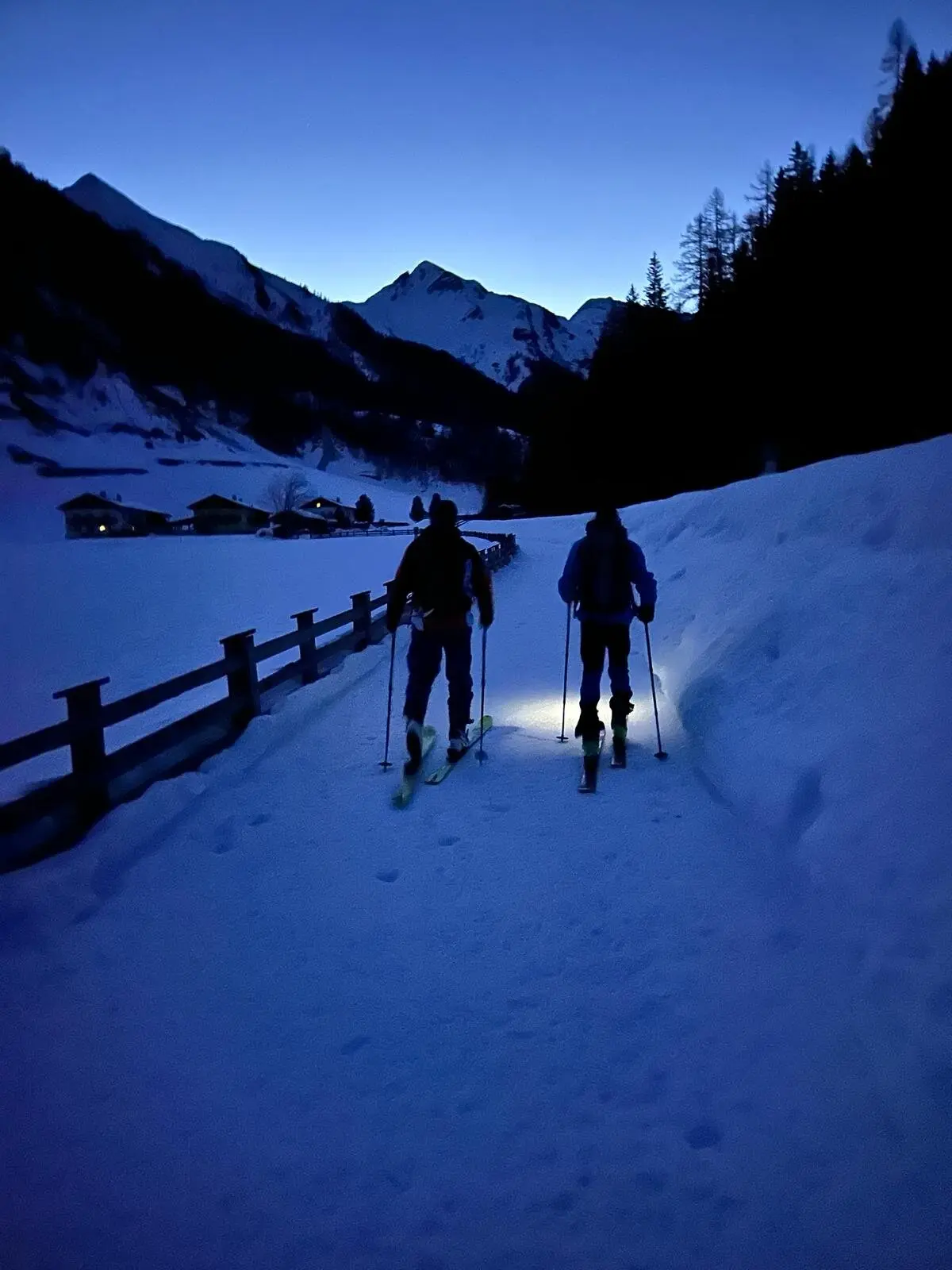 Zwei Personen mit Stirnlampen auf Skiern in verschneiter Landschaft bei Dämmerung. | © DAV Dortmund