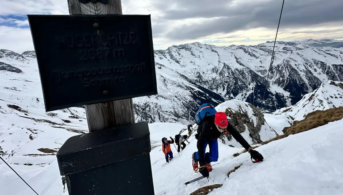 Gruppe von Skitourengeher*innen beim steilen Aufstieg am Hochschober, Gipfelschild im Vordergrund. | © DAV Dortmund