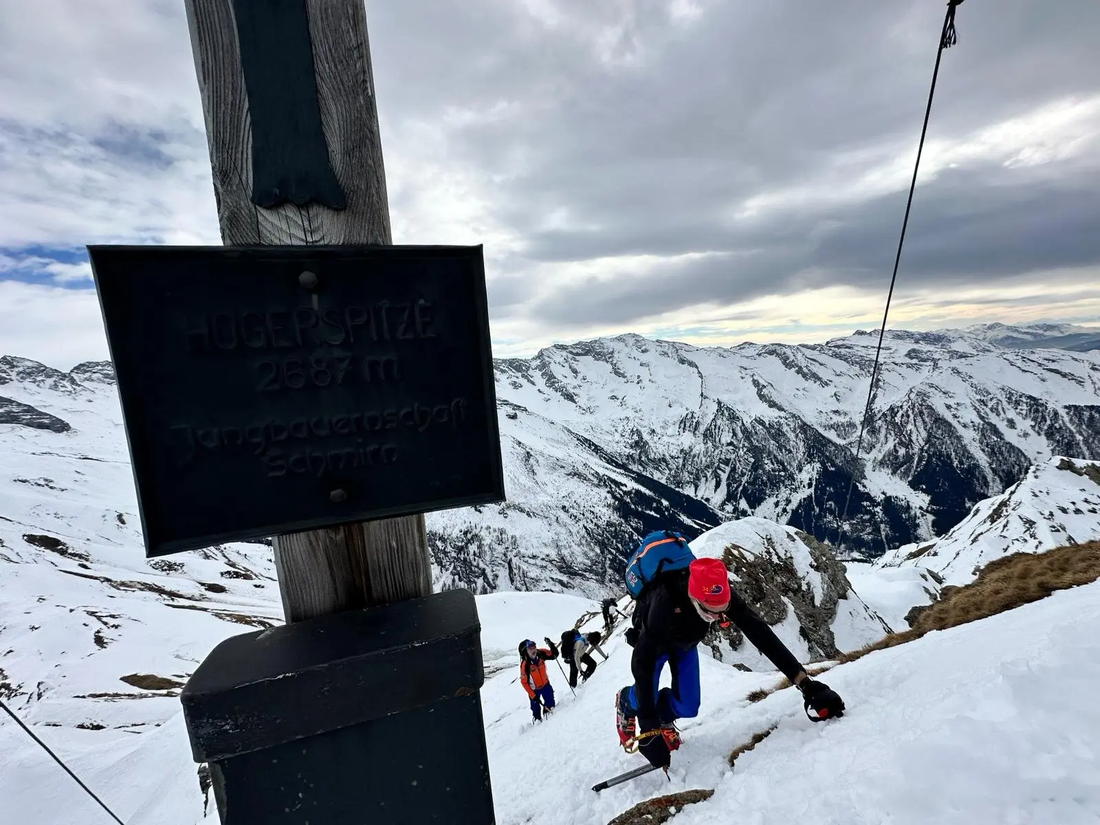 Gruppe von Skitourengeher*innen beim steilen Aufstieg am Hochschober, Gipfelschild im Vordergrund. | © DAV Dortmund