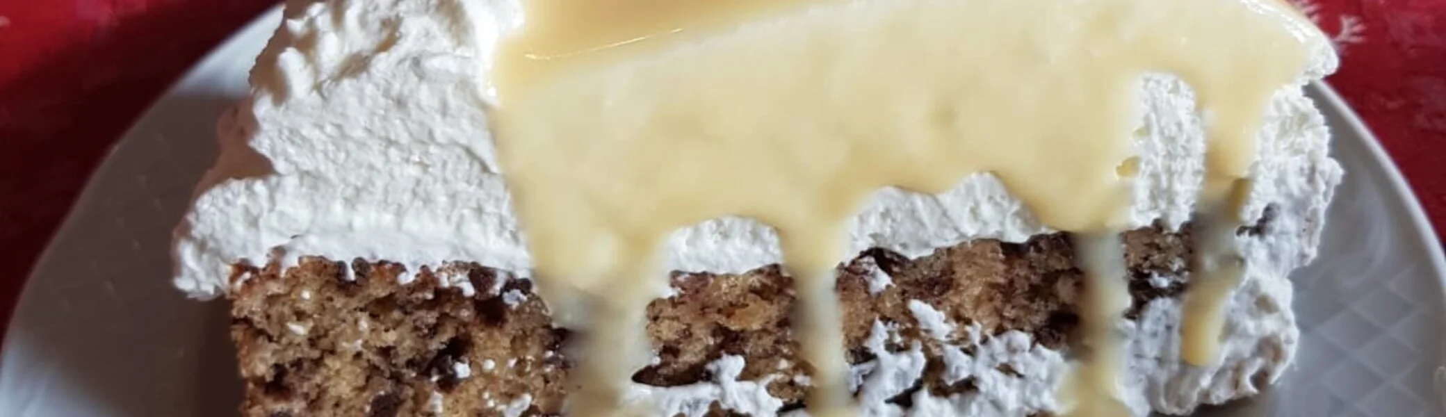 Ein Stück Nusskuchen mit Schlagsahne und Vanillesoße auf einem weißen Teller. | © DAV Dortmund