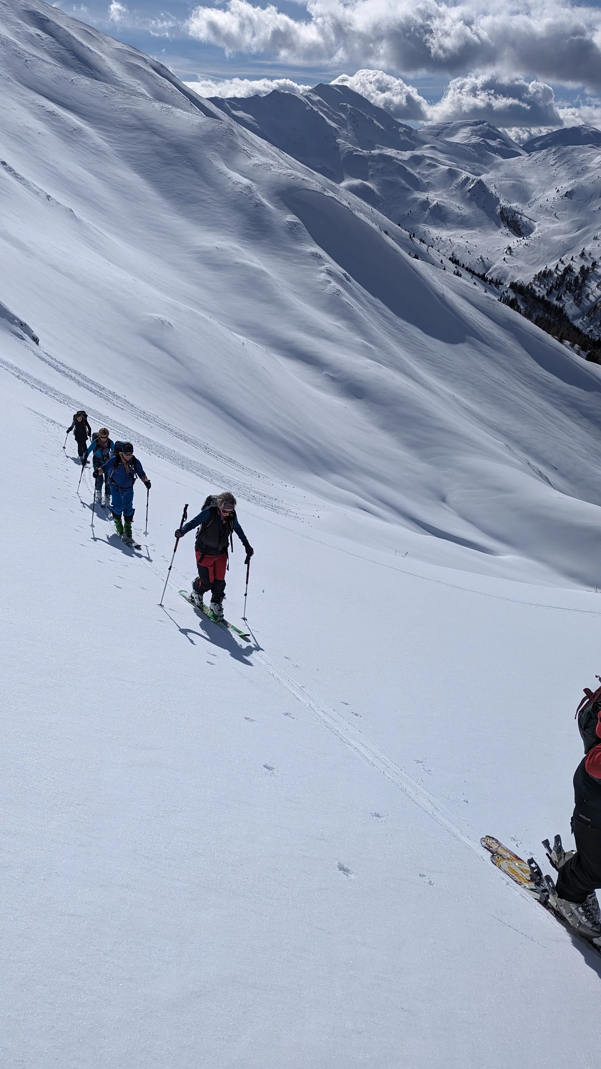 Fünf Personen mit Skiern steigen über einen weiten, verschneiten Hang bergauf. | © DAV Dortmund