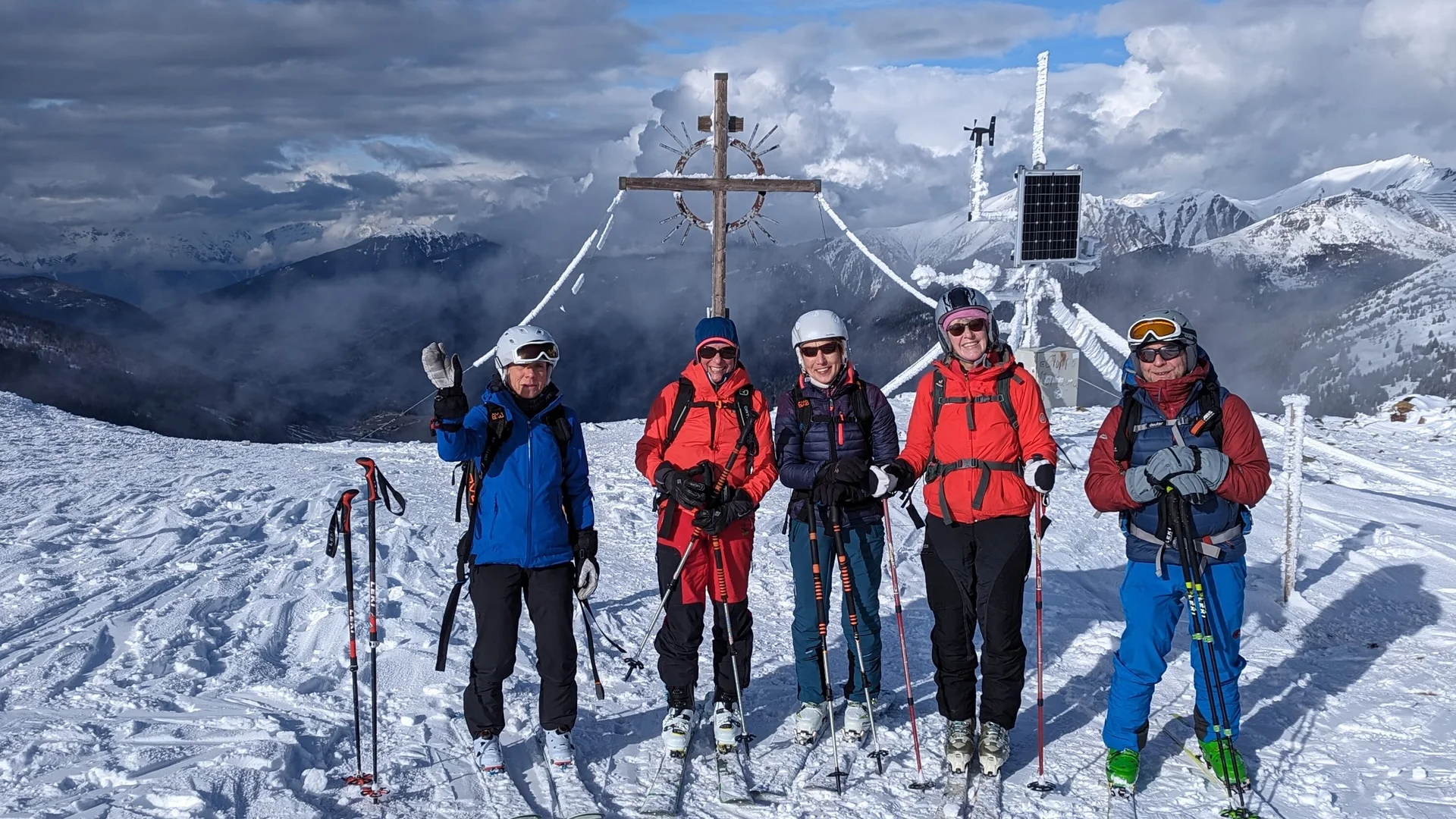 Fünf Skitourengeher*innen stehen vor einem Gipfelkreuz mit bewölktem Himmel im Hintergrund. | © DAV Dortmund