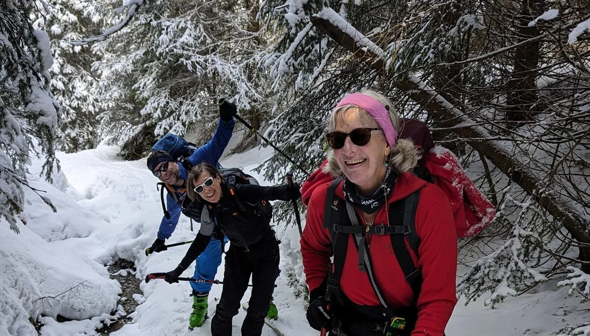 Drei Skitourengeher*innen steigen durch einen engen, verschneiten Waldweg auf. | © DAV Dortmund