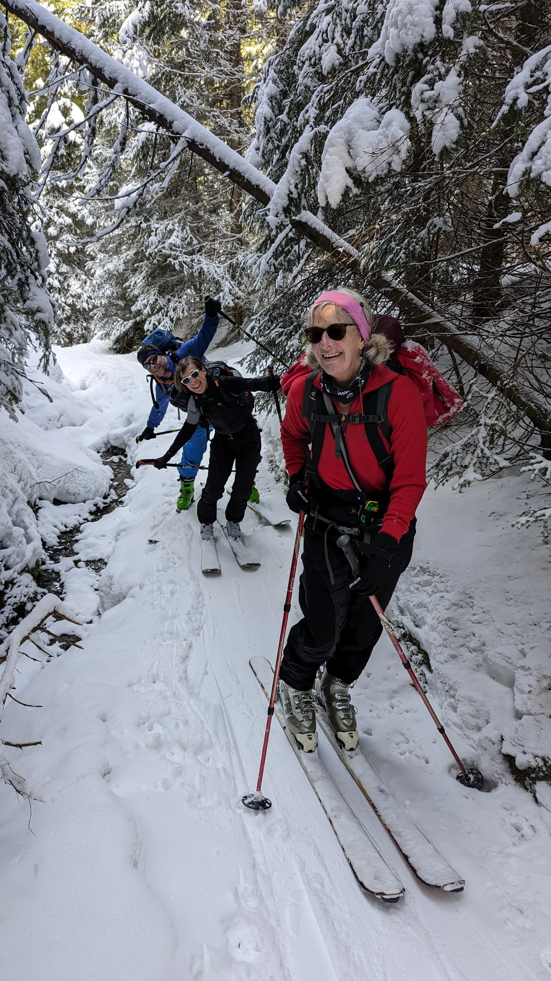 Drei Skitourengeher*innen steigen durch einen engen, verschneiten Waldweg auf. | © DAV Dortmund