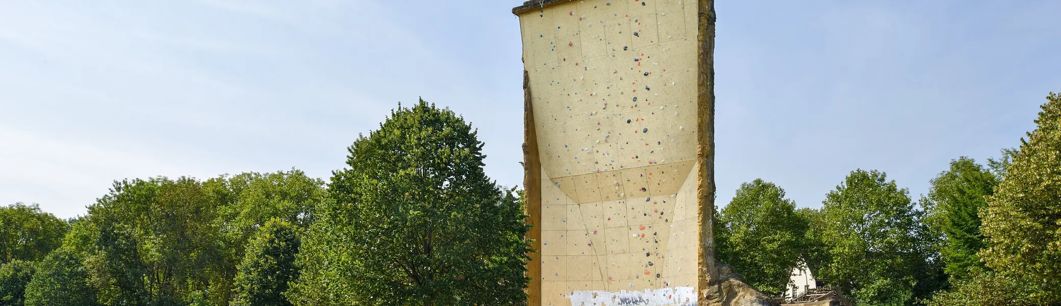 nsicht des Kletterturms mit sichtbarer beschraubter Kletterfläche, Wiese und Bänke. | © DAV Dortmund