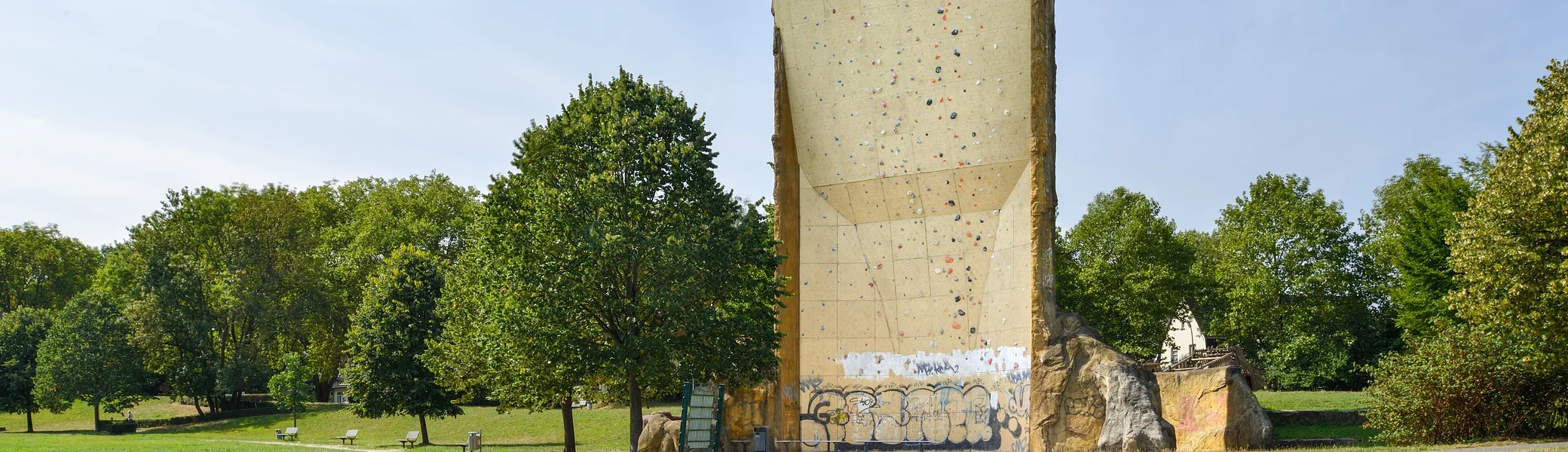 nsicht des Kletterturms mit sichtbarer beschraubter Kletterfläche, Wiese und Bänke. | © DAV Dortmund