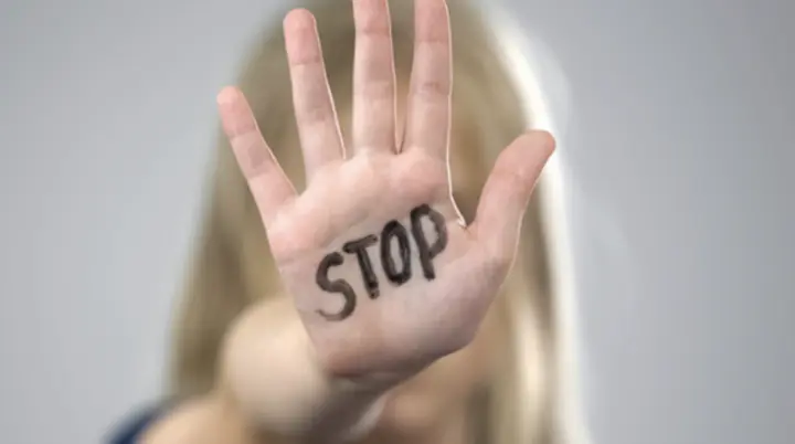 Hand mit aufgeschriebenem Wort „STOP“, im Hintergrund eine Frau. Symbol für Schutz und Prävention. | © DAV Dortmund