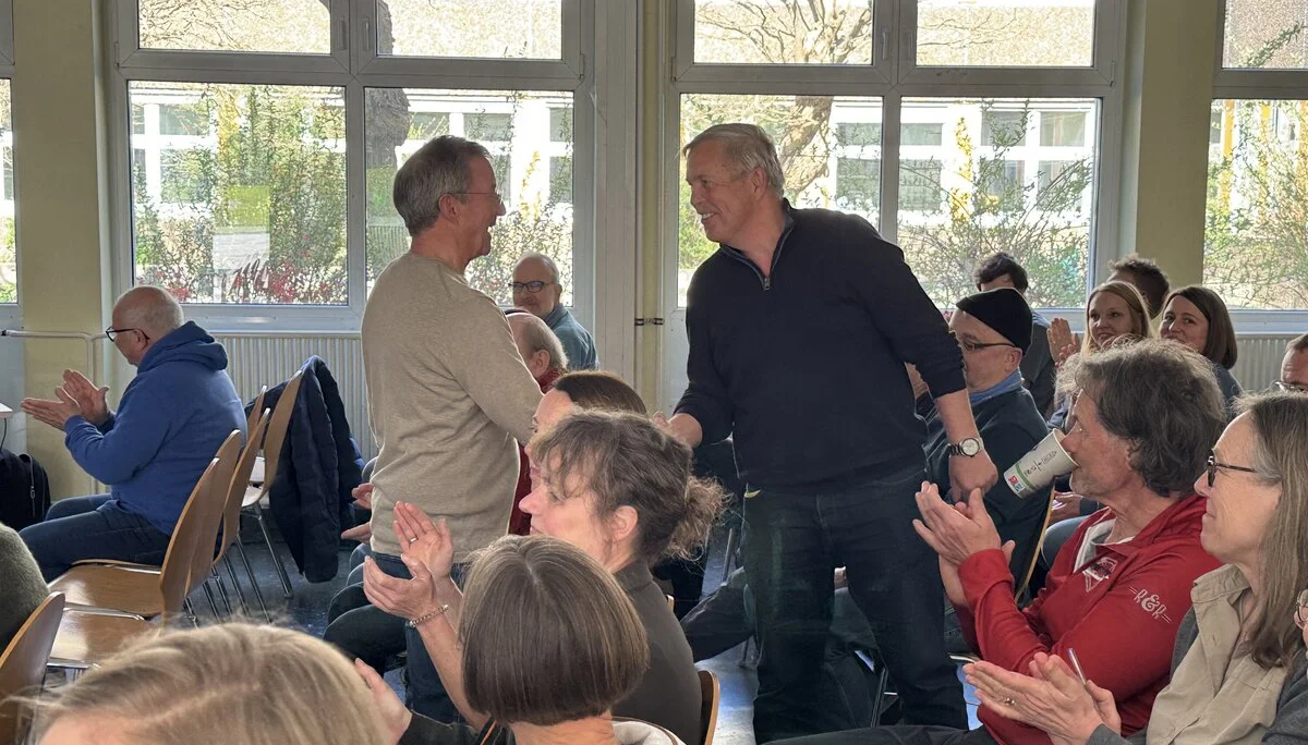 Zwei Männer stehen inmitten einer applaudierenden Gruppe in einem Veranstaltungsraum. | © DAV Dortmund