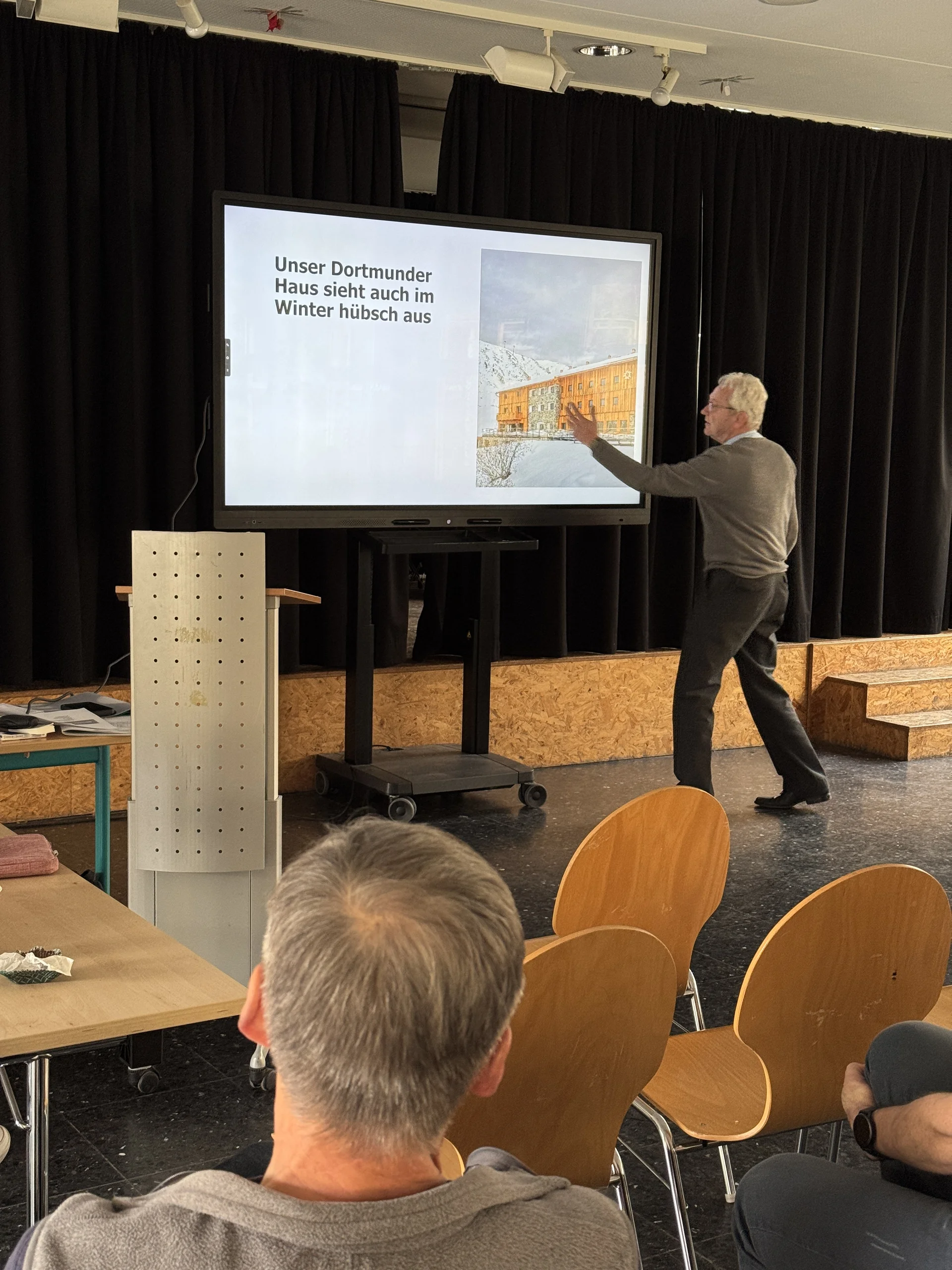 Person zeigt auf eine Folie mit Visualisierung des geplanten DAV-Zentrums, Vortragssituation. | © DAV Dortmund