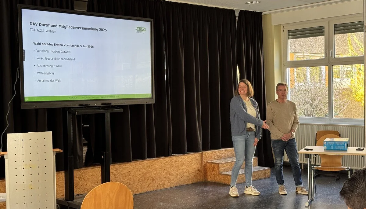 Zwei Personen stehen auf einer Bühne und schütteln sich bei der Mitgliederversammlung des DAV Dortmund die Hand. | © DAV Dortmund
