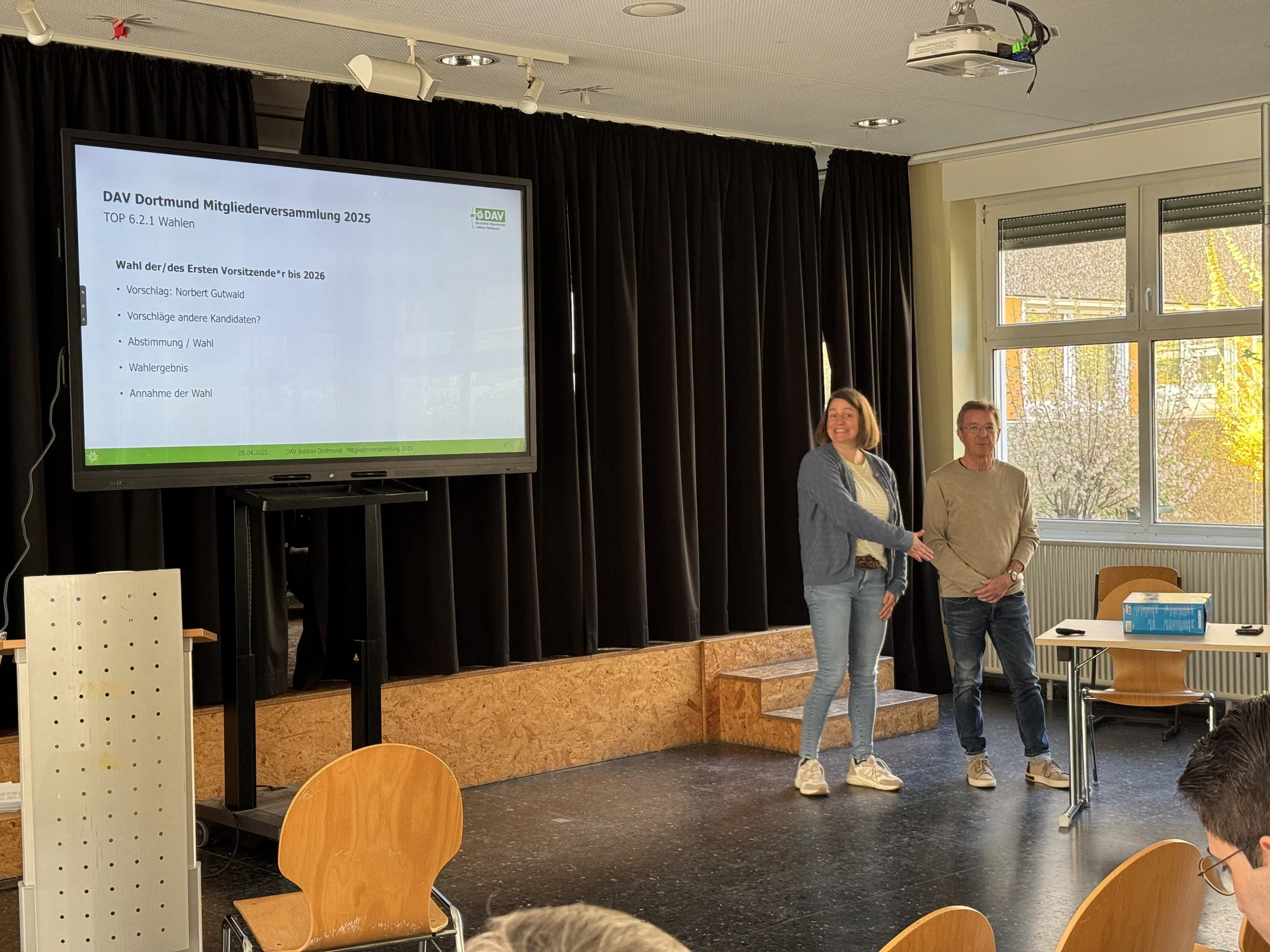 Zwei Personen stehen auf einer Bühne und schütteln sich bei der Mitgliederversammlung des DAV Dortmund die Hand. | © DAV Dortmund