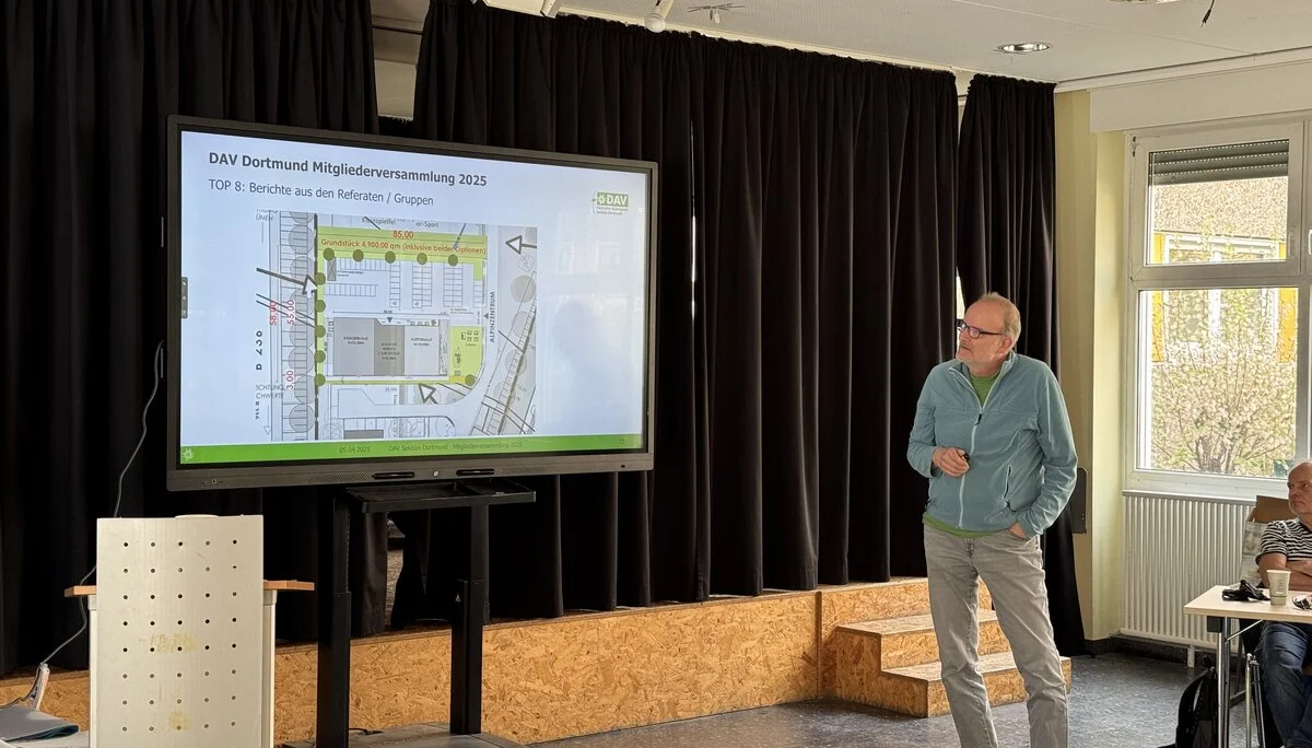 Ein Mann präsentiert einen Bauplan des DAV-Zentrums auf einer großen Leinwand während der Mitgliederversammlung. | © DAV Dortmund