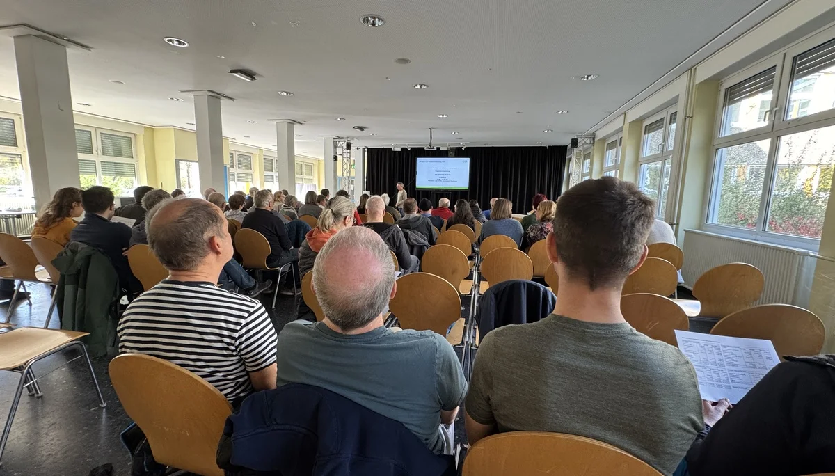 Viele Teilnehmer*innen sitzen in einem großen, hellen Saal und verfolgen eine Präsentation auf der Bühne. | © DAV Dortmund