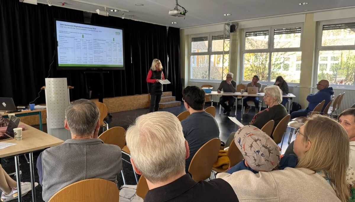 Eine Frau hält einen Vortrag vor Publikum bei der DAV Dortmund Mitgliederversammlung, eine Präsentation ist im Hintergrund sichtbar. | © DAV Dortmund