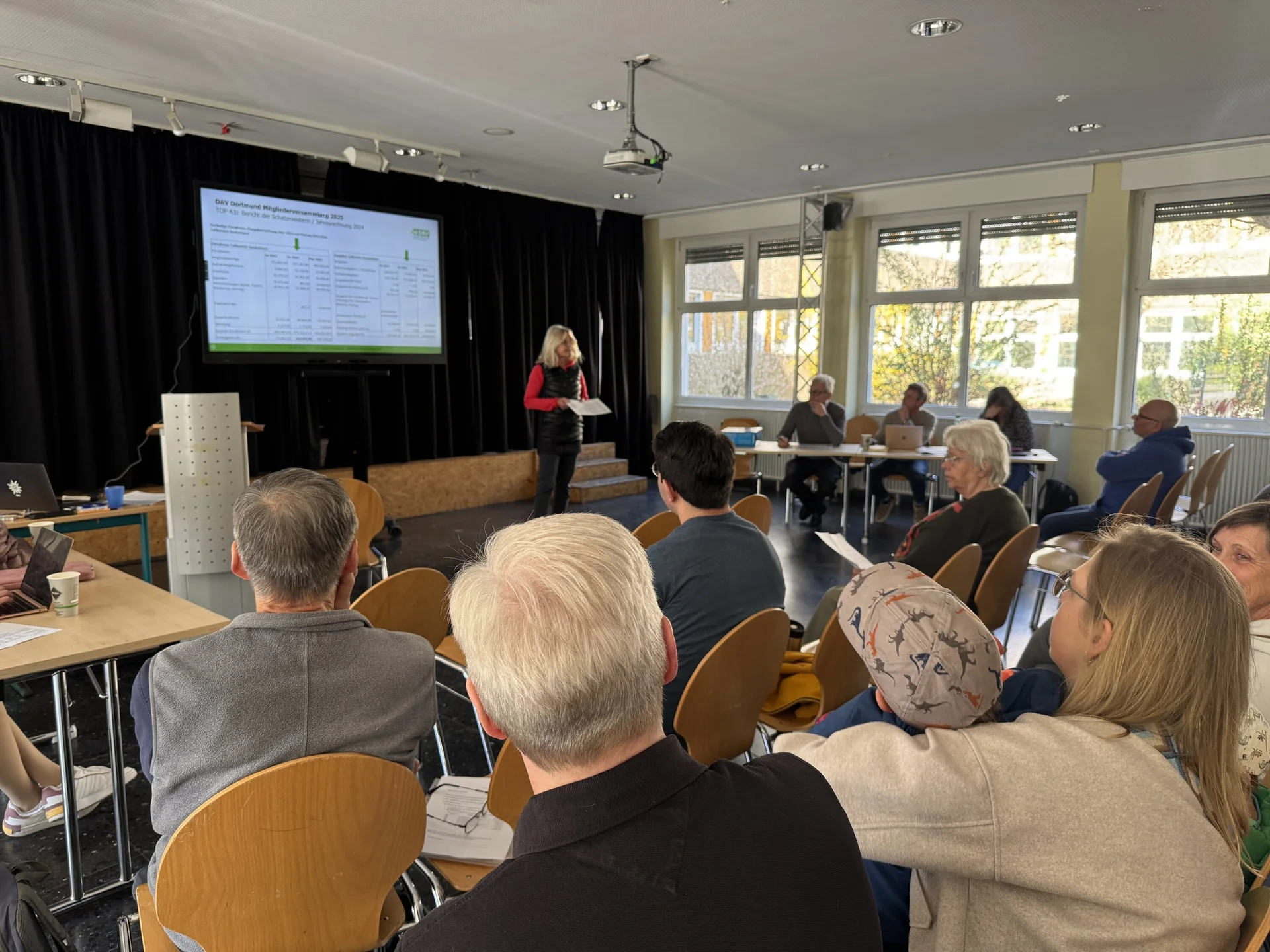 Eine Frau hält einen Vortrag vor Publikum bei der DAV Dortmund Mitgliederversammlung, eine Präsentation ist im Hintergrund sichtbar. | © DAV Dortmund