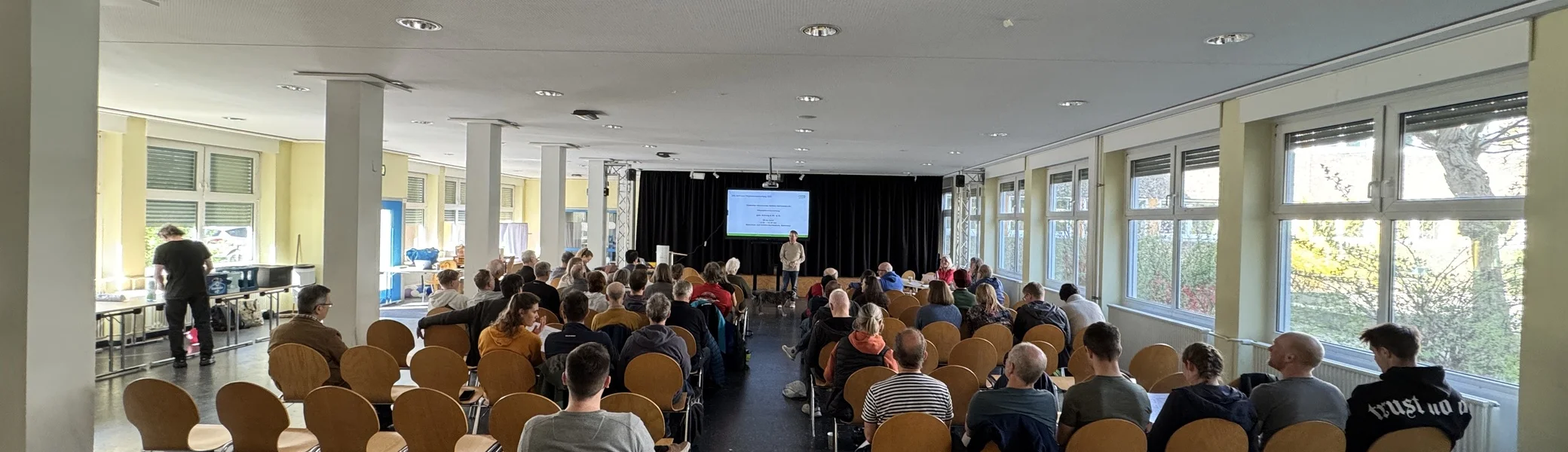 Zahlreiche Personen sitzen in Reihen und verfolgen die Präsentation bei der DAV Dortmund Mitgliederversammlung. | © DAV Dortmund