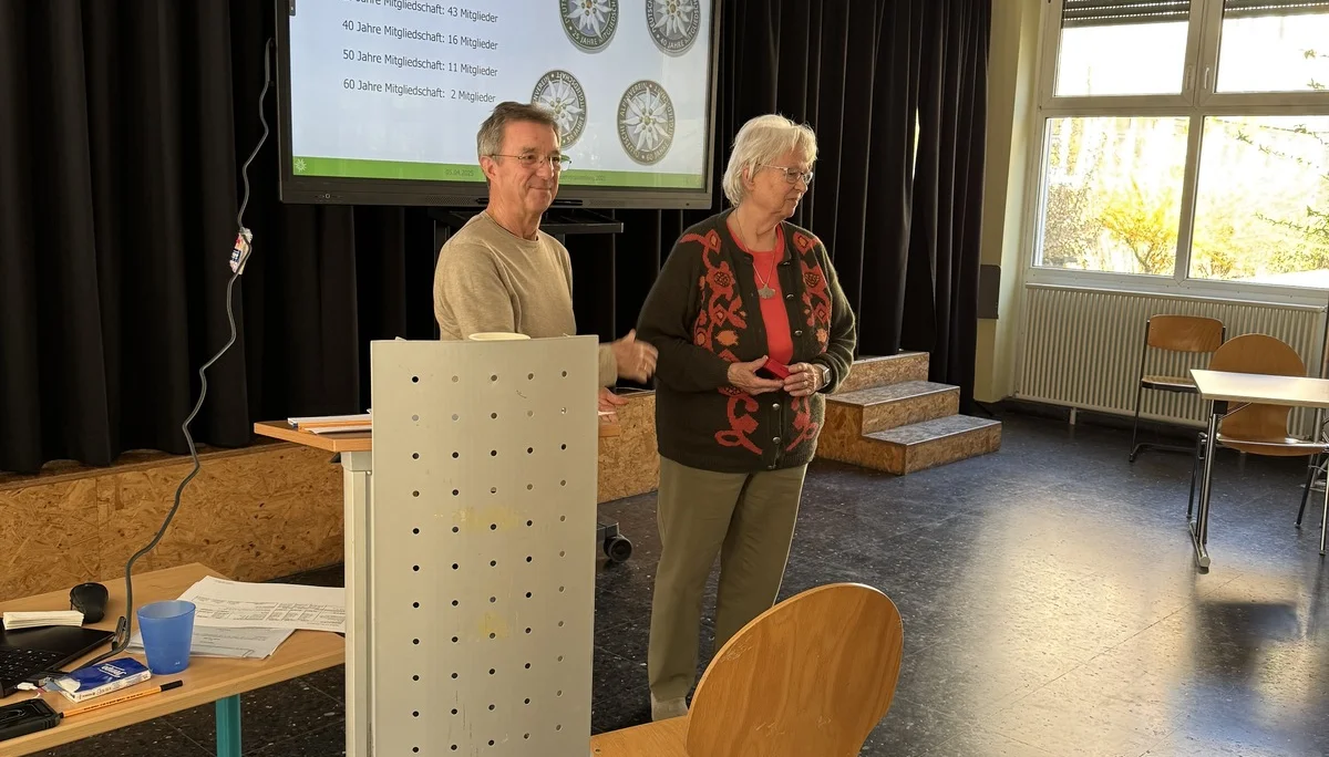 Eine Frau und ein Mann stehen auf der Bühne der Mitgliederversammlung und präsentieren Informationen zur Vereinsmitgliedschaft. | © DAV Dortmund