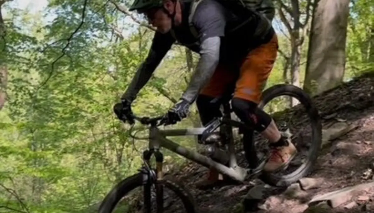 Mountainbiker mit Protektoren fährt konzentriert eine steile Passage mit Laub und Wurzeln im Wald hinunter. | © DAV Dortmund