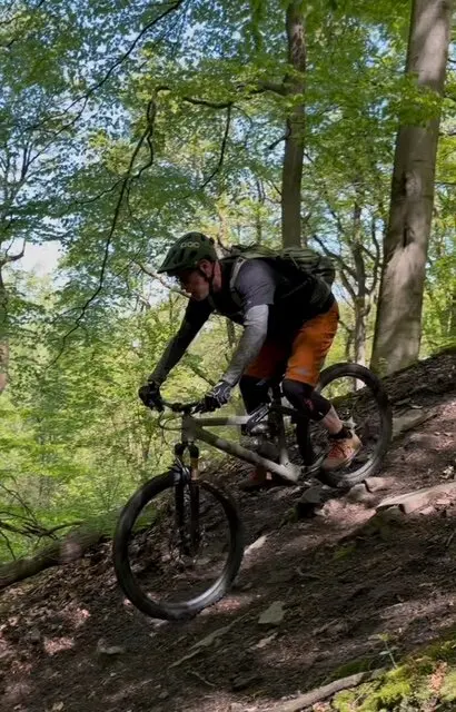 Mountainbiker mit Protektoren fährt konzentriert eine steile Passage mit Laub und Wurzeln im Wald hinunter. | © DAV Dortmund
