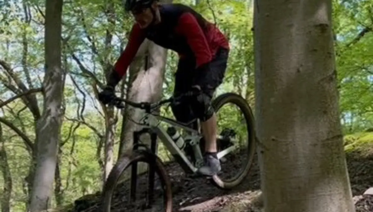 Person fährt mit Helm und Schutzkleidung auf einem steilen Trail zwischen Bäumen bergab. | © DAV Dortmund