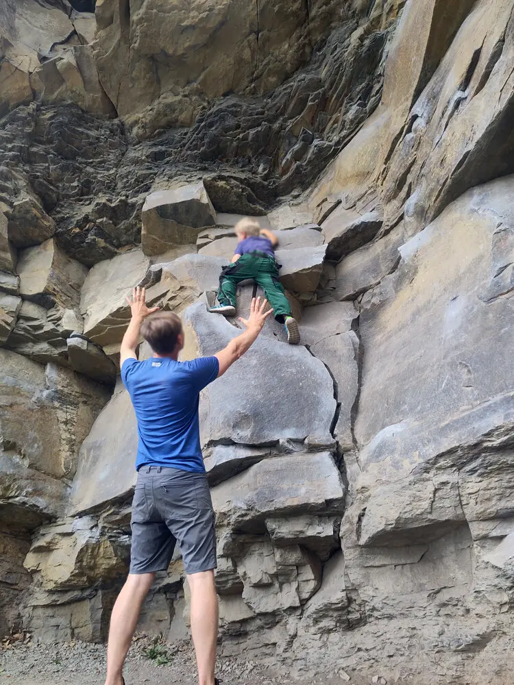 Ein Erwachsener sichert ein Kind, das in einer Felswand klettert. Beide befinden sich im unteren Bereich der Route. | © DAV Dortmund