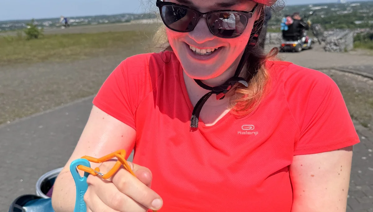 Frau mit Helm und Sonnenbrille isst Schokolade mit Gabel während einer Radtour. | © DAV Dortmund