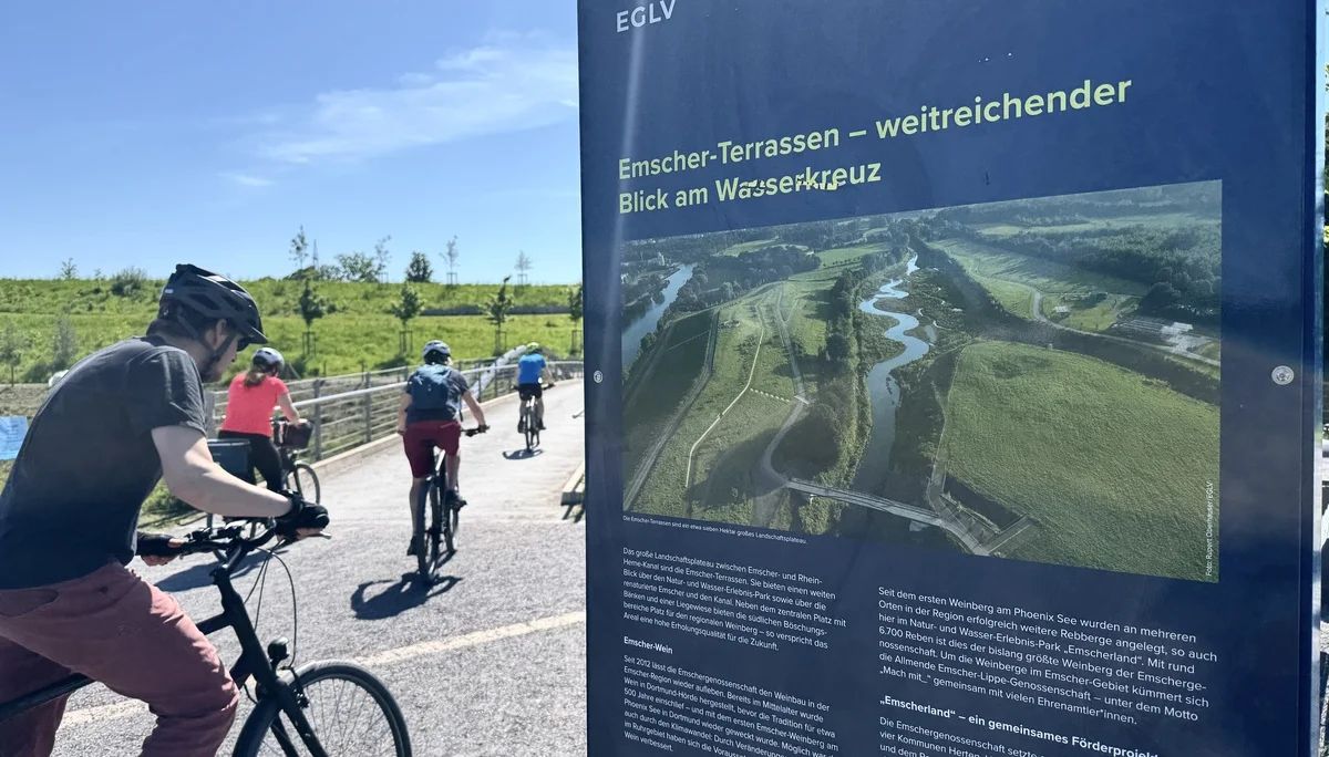 Radfahrende halten an einer Infotafel mit Karte und Beschreibung der Emscher-Terrassen. | © DAV Dortmund