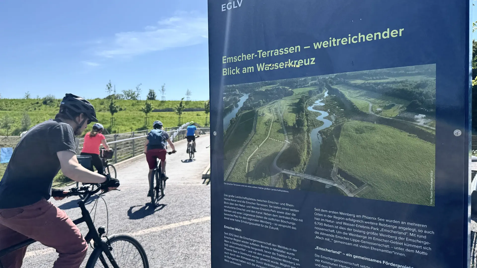 Radfahrende halten an einer Infotafel mit Karte und Beschreibung der Emscher-Terrassen. | © DAV Dortmund