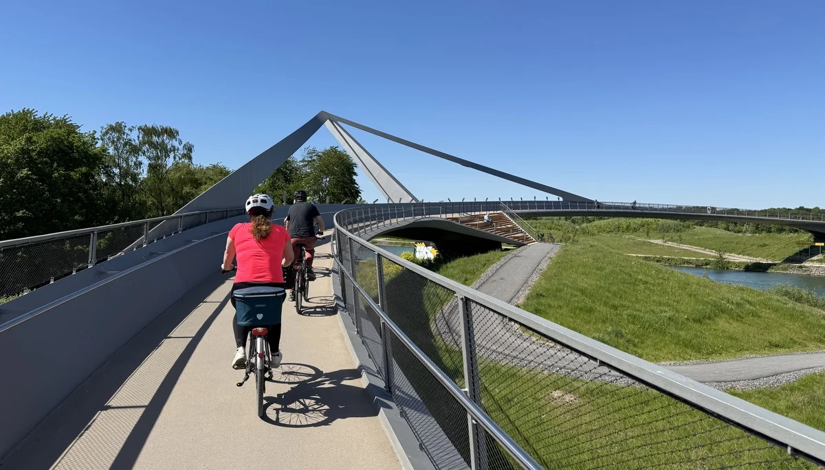 Radfahrer*innen überqueren eine moderne Brücke mit markanter Konstruktion und Geländern. | © DAV Dortmund