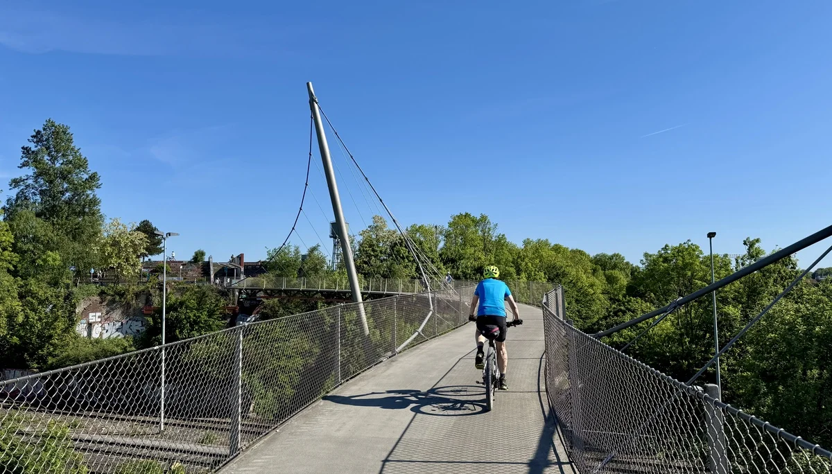Radfahrer überquert eine moderne Hängebrücke mit schrägen Seilträgern. | © DAV Dortmund