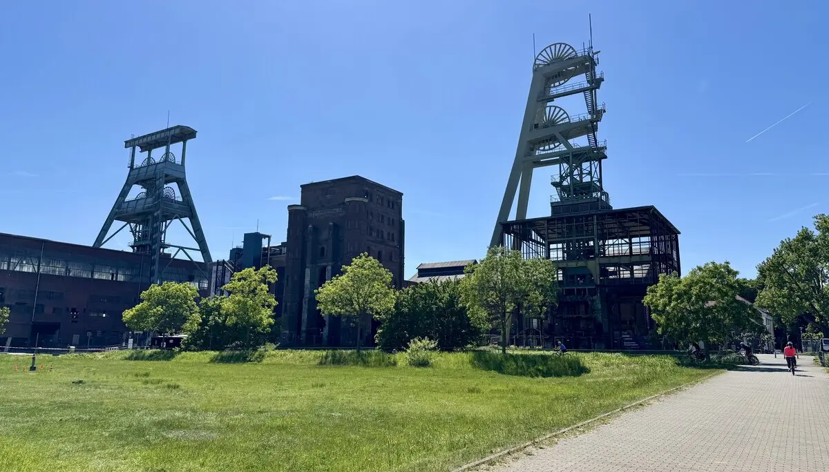 Alte Fördertürme und Gebäude eines ehemaligen Bergwerks vor blauem Himmel. | © DAV Dortmund