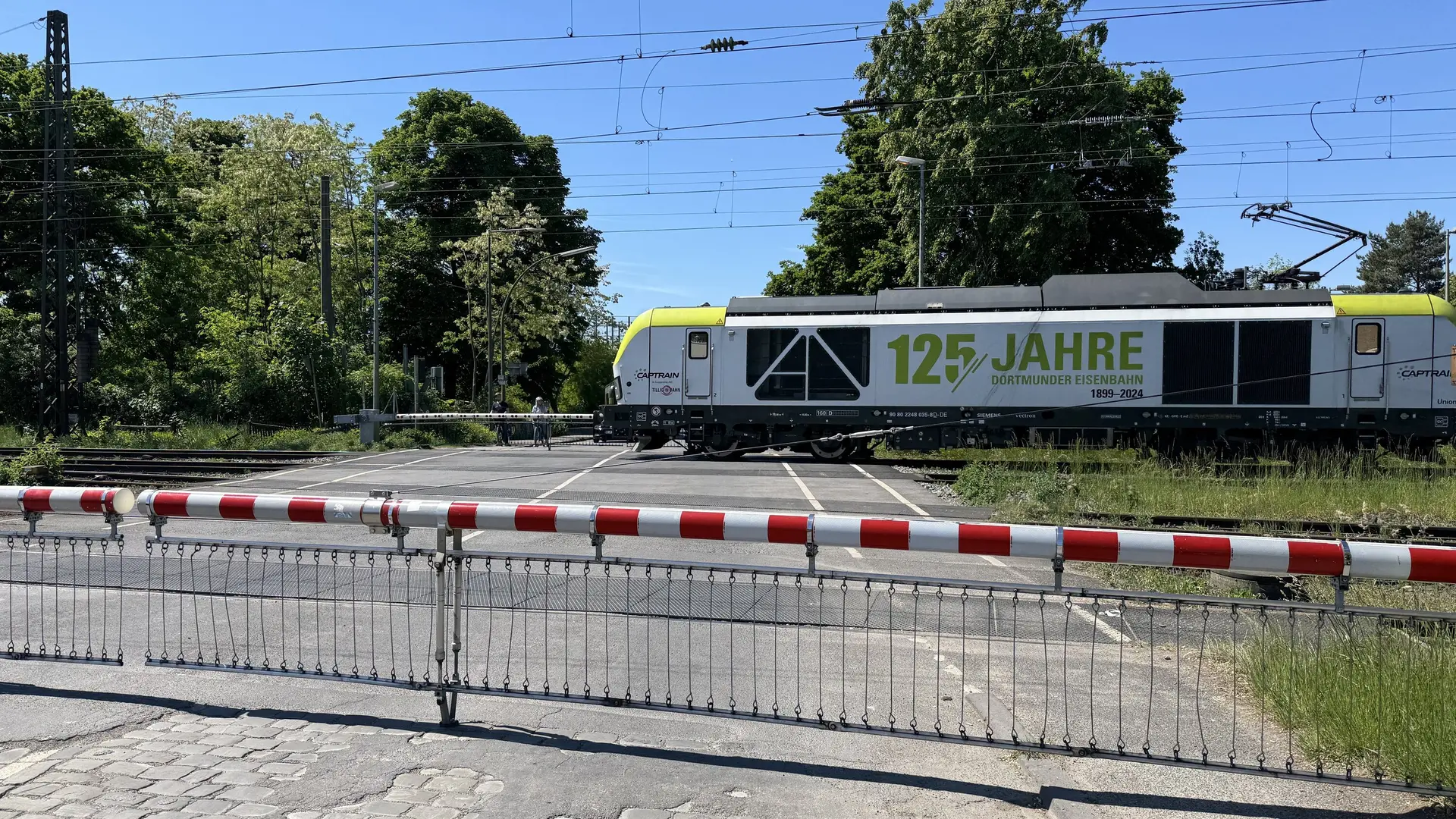 Lokomotive mit Aufschrift „125 Jahre“ passiert einen geschlossenen Bahnübergang. | © DAV Dortmund
