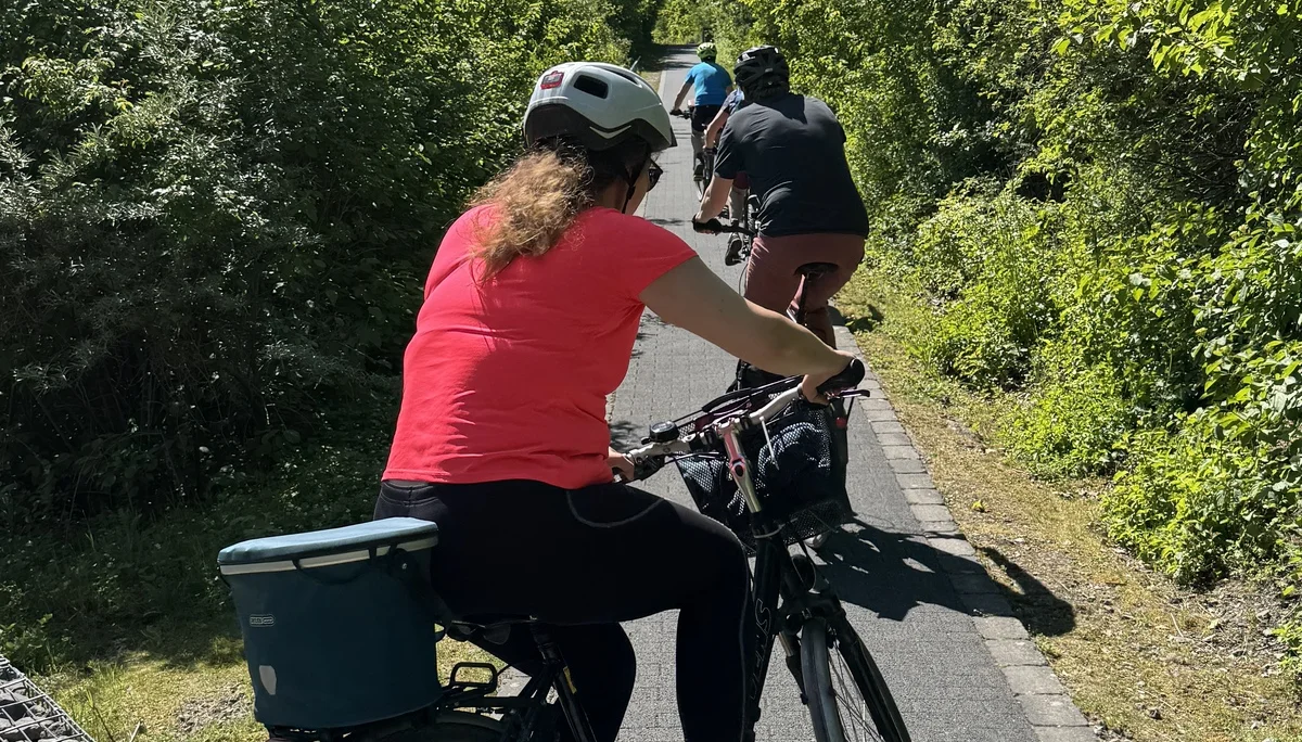 Radfahrer*innen fahren auf einem schmalen, leicht ansteigenden Weg durch grüne Vegetation. | © DAV Dortmund
