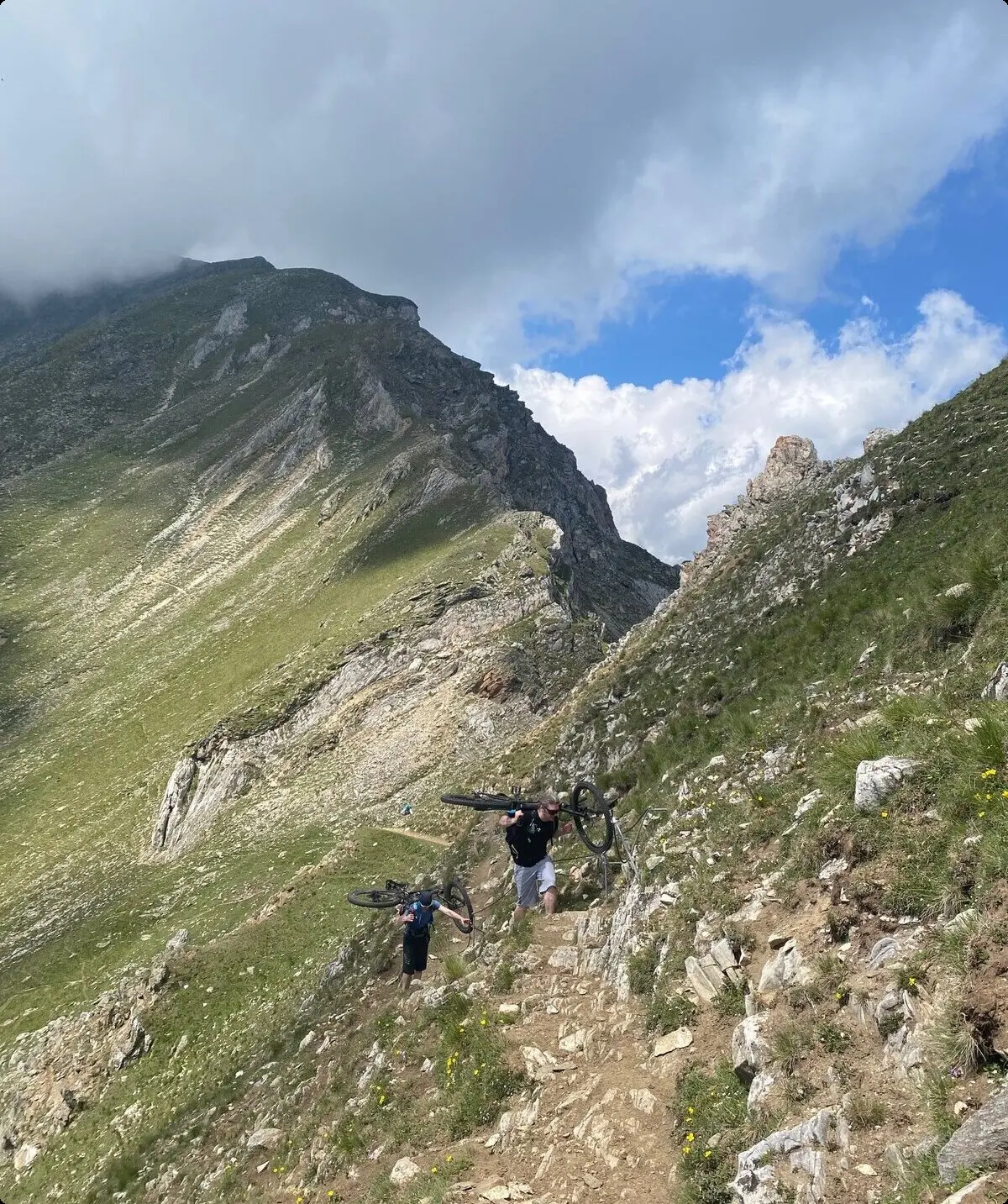 Zwei Personen tragen ihre Mountainbikes auf einem schmalen Bergpfad. | © DAV Dortmund