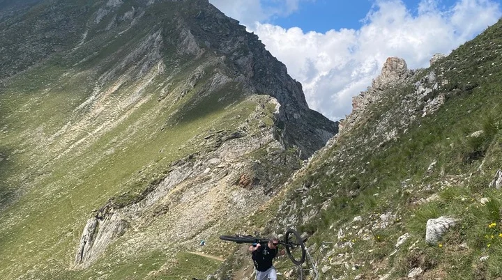 Zwei Personen tragen ihre Mountainbikes auf einem schmalen Bergpfad. | © DAV Dortmund