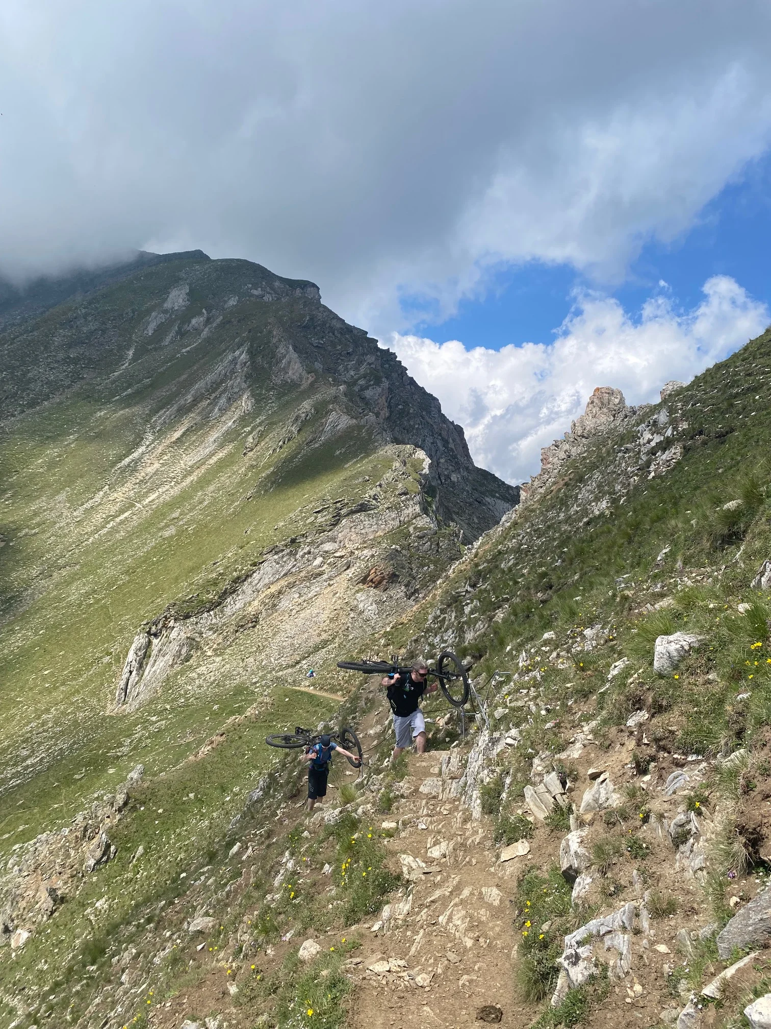 Zwei Personen tragen ihre Mountainbikes auf einem schmalen Bergpfad. | © DAV Dortmund