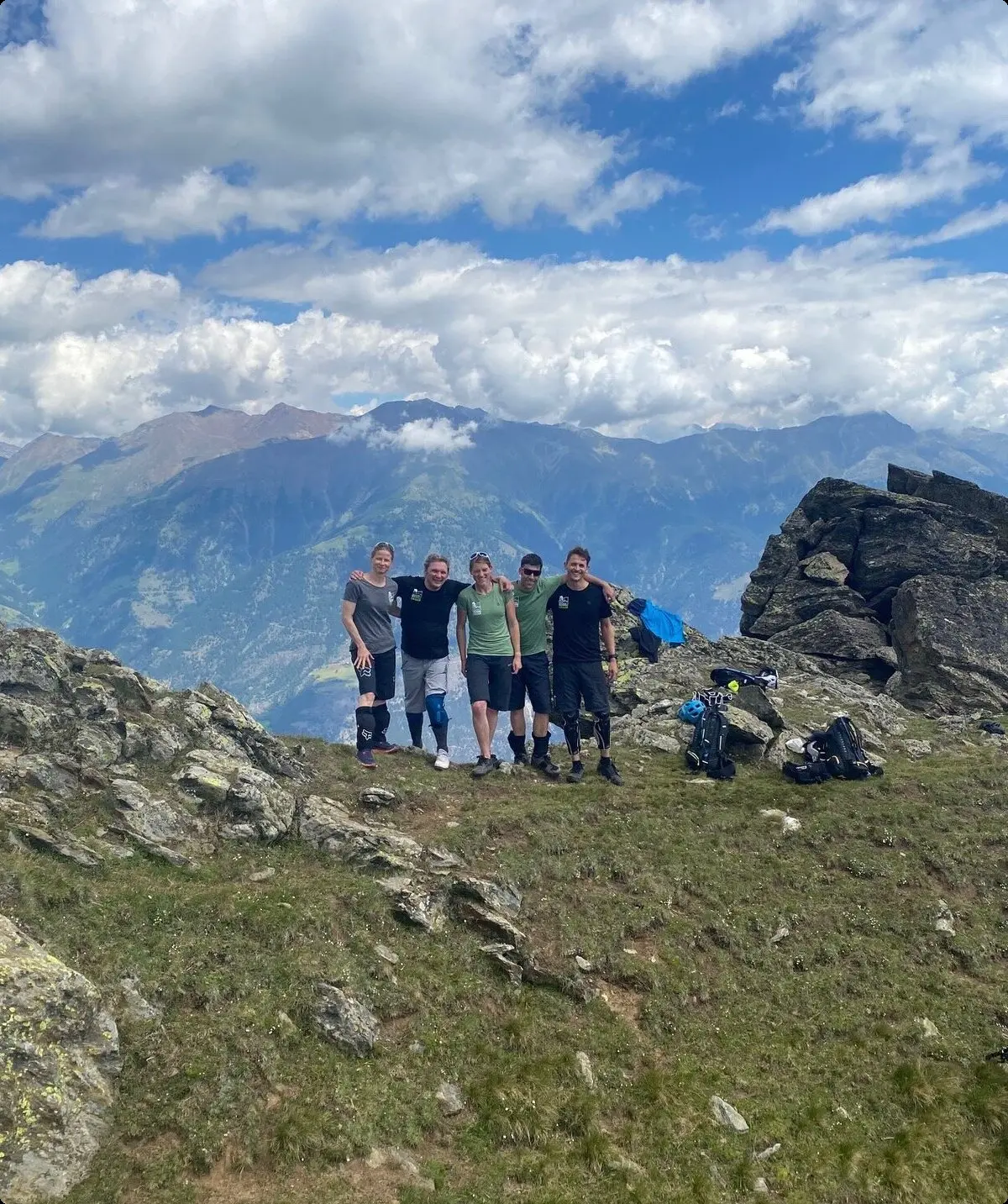Gruppe von Mountainbikern steht auf einem felsigen Gipfel mit Blick auf das Bergpanorama. | © DAV Dortmund