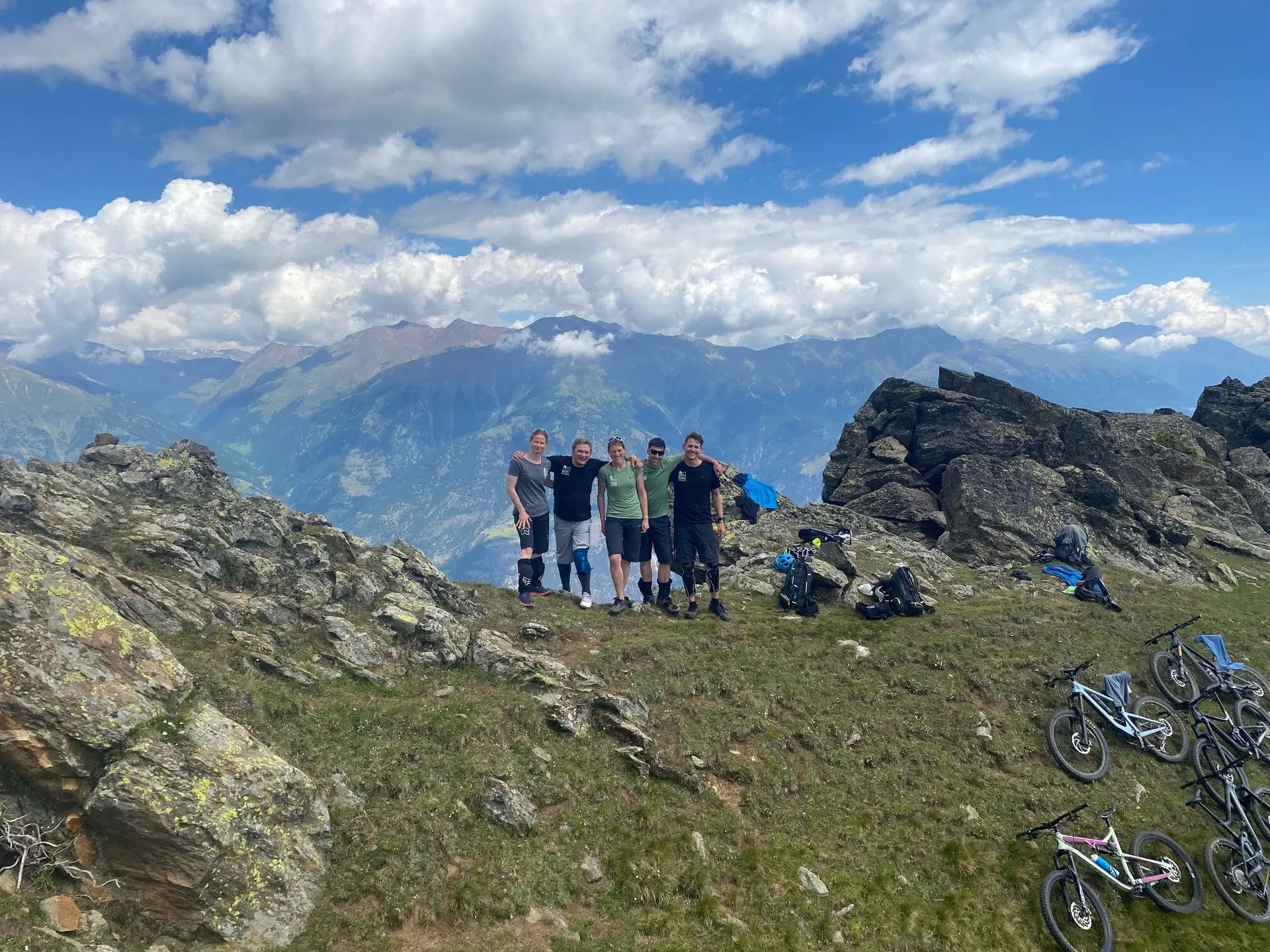 Gruppe von Mountainbikern steht auf einem felsigen Gipfel mit Blick auf das Bergpanorama. | © DAV Dortmund