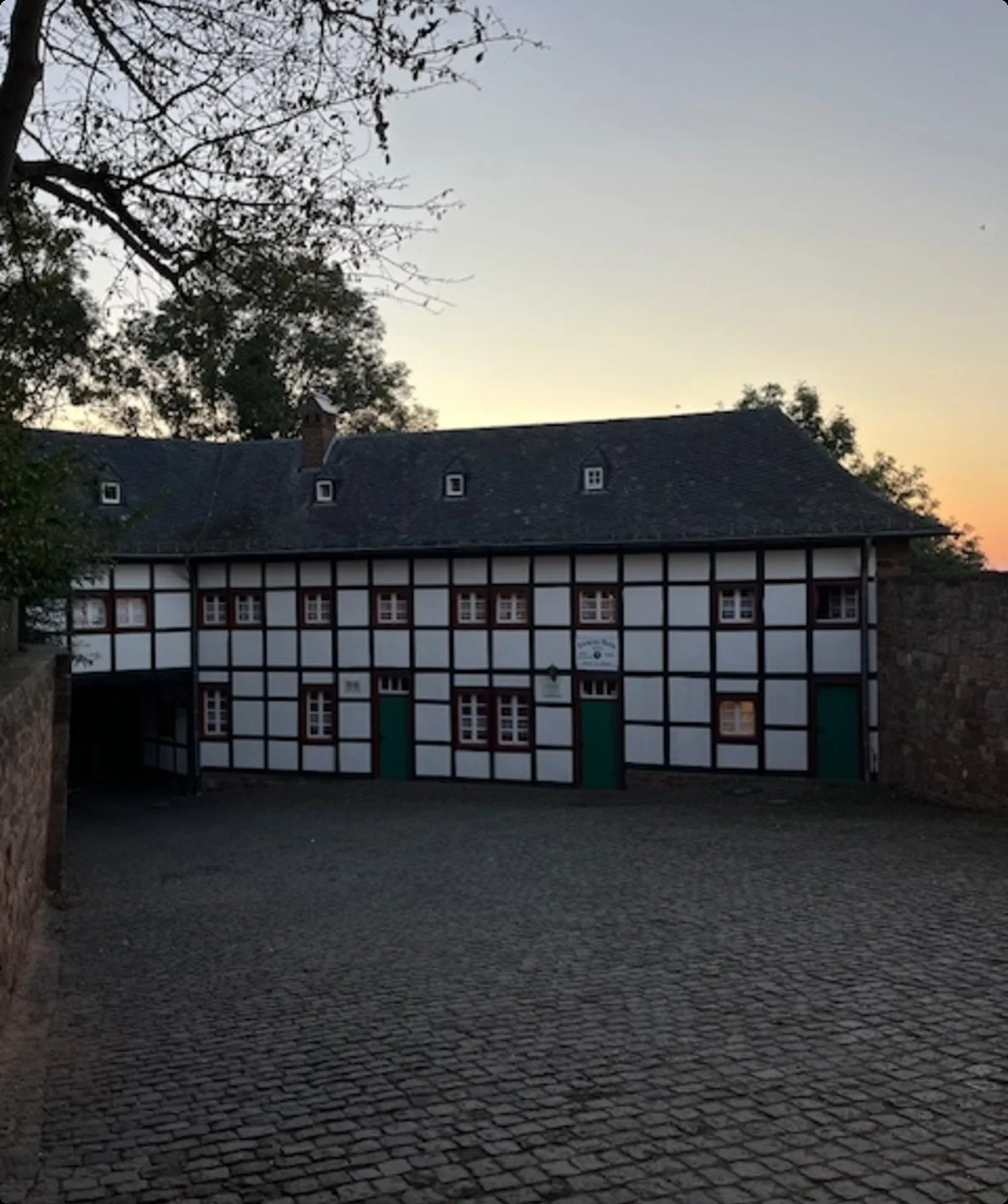 Ein altes Fachwerkhaus mit Kopfsteinpflaster im Hof, aufgenommen bei Sonnenuntergang. | © DAV Dortmund