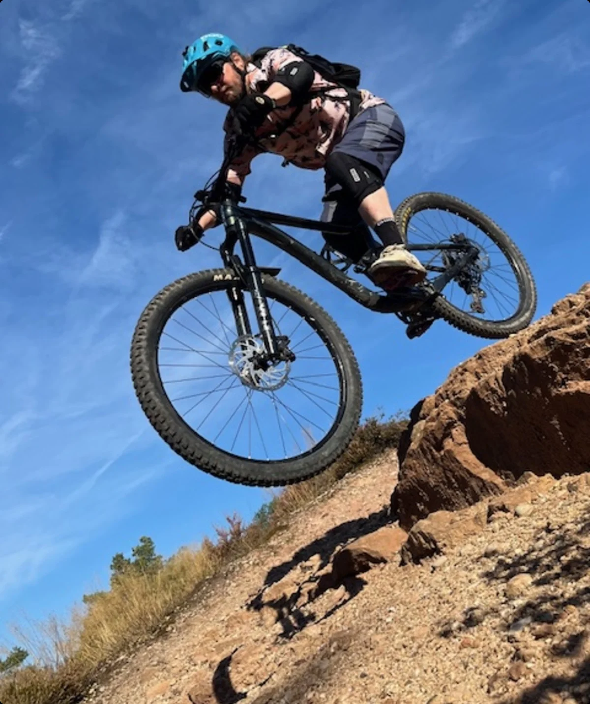 Ein Biker springt mit seinem Mountainbike über eine Felskante auf einem sonnigen Trail. | © DAV Dortmund