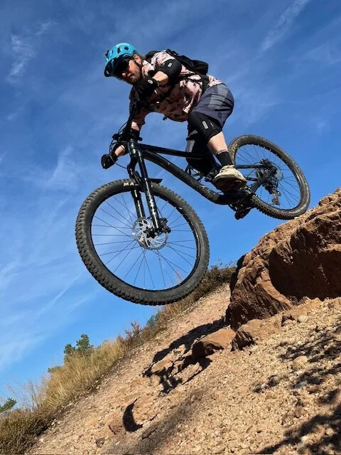 Ein Biker springt mit seinem Mountainbike über eine Felskante auf einem sonnigen Trail. | © DAV Dortmund