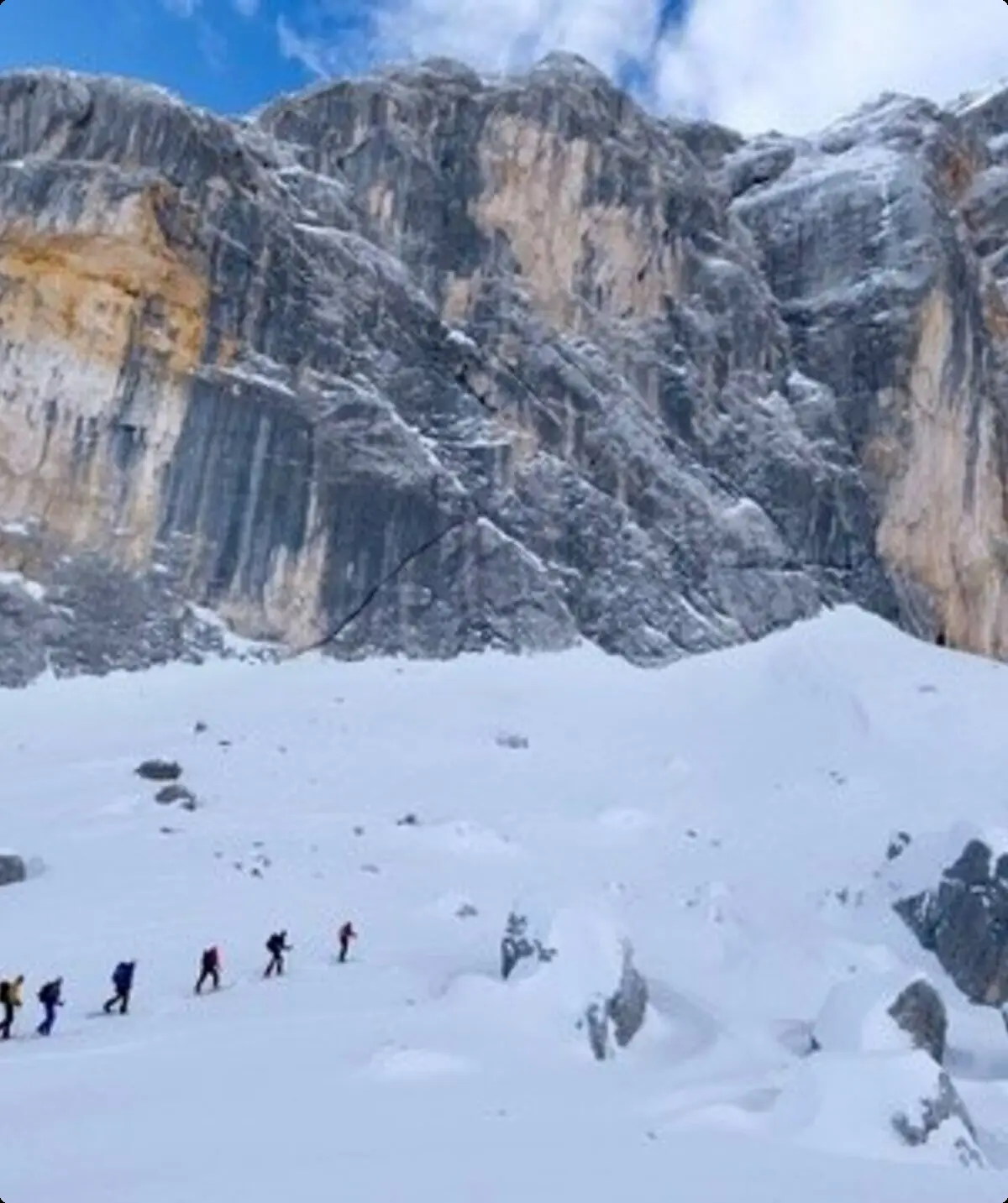 Eine Gruppe Skitourengeher*innen geht durch tiefen Schnee in einer spektakulären Winterlandschaft mit hohen Felsen. | © DAV Dortmund