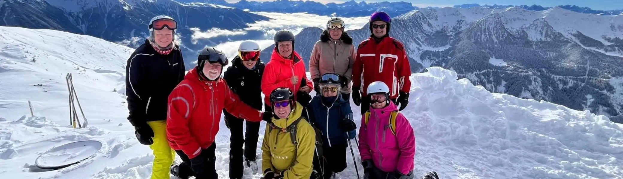 Neun Skifahrer*innen stehen auf einem verschneiten Gipfel mit beeindruckender Aussicht. | © DAV Dortmund