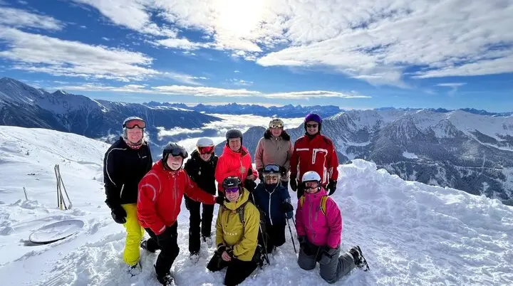 Neun Skifahrer*innen stehen auf einem verschneiten Gipfel mit beeindruckender Aussicht. | © DAV Dortmund