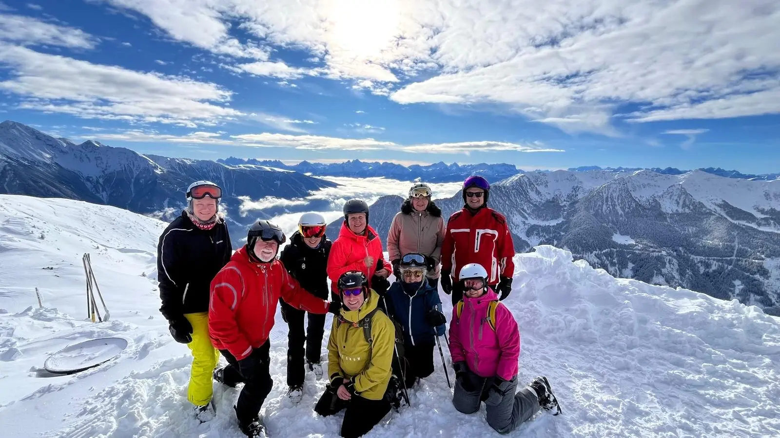 Neun Skifahrer*innen stehen auf einem verschneiten Gipfel mit beeindruckender Aussicht. | © DAV Dortmund